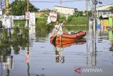 Warga menggunakan perahu untuk melintasi banjir yang merendam Perumahan Garden City Residence, Periuk, Kota Tangerang, Banten, Minggu (24/11/2024). Banjir merendam ratusan rumah warga sejak Sabtu (23/11/2024) malam yang disebabkan jebolnya turap kali sepanjang 10 meter karena tidak kuat menahan derasnya arus air kali saat curah hujan tinggi. ANTARA FOTO/Sulthony Hasanuddin/gp