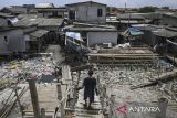 Warga berjalan di Kampung Dadap yang dipenuhi sampah di Kosambi, Kabupaten Tangerang, Banten, Minggu (24/11/2024). Sebagian warga di kampung tersebut masih membuang sampah rumah tangga sembarangan dan membutuhkan penerapan sistem pengelolaan sampah agar tidak menimbulkan penyakit di pemukiman tersebut. ANTARA FOTO/Sulthony Hasanuddin/gp