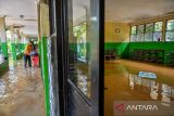 Penjaga sekolah memeriksa lorong sekolah yang terdampak banjir di SMPN 1 Bojongsoang, Kabupaten Bandung, Jawa Barat, Minggu (24/11/2024). Penjaga sekolah mengungkapkan sejak Jumat (22/11/2024) sekolah tersebut terendam banjir akibat intensitas hujan yang tinggi dan luapan Sungai Citarum dan fasilitas sekolah tidak dapat digunakan karena debit air yang masih tinggi. ANTARA FOTO/Raisan Al Farisi/agr
