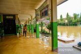 Penjaga sekolah berusaha membuang air yang menggenangi lorong sekolah yang terdampak banjir di SMPN 1 Bojongsoang, Kabupaten Bandung, Jawa Barat, Minggu (24/11/2024). Penjaga sekolah mengungkapkan sejak Jumat (22/11/2024) sekolah tersebut terendam banjir akibat intensitas hujan yang tinggi dan luapan Sungai Citarum dan fasilitas sekolah tidak dapat digunakan karena debit air yang masih tinggi. ANTARA FOTO/Raisan Al Farisi/agr
