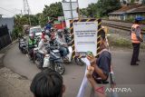 Anggota Railfans Cimahi menunjukan poster keselamatan saat sosialisasi keselamatan perlintasan sebidang di Ngamprah, Kabupaten Bandung Barat, Jawa Barat, Minggu (24/11/2024). PT KAI Daop 2 Bandung bersama Railfans Cimahi dan relawan perlintasan menggelar sosialisasi keselamatan perlintasan sebidang yang bertujuan untuk meningkatkan kesadaran masyarakat akan pentingnya mentaati peraturan lalu lintas saat melintas di perlintasan sebidang kereta api demi keselamatan. ANTARA FOTO/Abdan Syakura/agr
