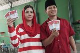 Calon Bupati Trenggalek Mochamad Nur arifin (kanan), didampingi istrinya yang anggota DPRD RI, Novita Hardini (kiri), menunjukkan surat suara sebelum mencoblosnya dan memasukkan ke dalam kotak suara di TPS 02 Kelurahan Surondakan, Trenggalek, Jawa Timur, Rabu (27/11/2024). Bermodal dukungan delapan partai politik, petahana Bupati Arifin berpasangan dengan wakilnya, Syah Muhammad natanegara, kembali maju dalam bursa Pilkada Trenggalek 2024 sebagai calon tunggal melawan kotak kosong. ANTARA Jatim/Destyan Sujarwoko/mas.