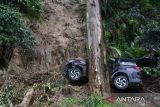 Warga melihat truk yang terhempas material tanah longsor di kawasan tikungan PDAM Tirtanadi, Sibolangit, Deli Serdang, Sumatera Utara, Rabu (27/11/2024). Bencana tanah longsor yang terjadi pada Selasa (26/11) malam tersebut mengakibatkan 25 warga luka-luka, dan empat warga dinyatakan meninggal dunia serta jalur utama Medan-Berastagi dan sebaliknya lumpuh total. ANTARA FOTO/Fransisco Carolio/