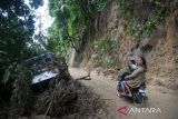 Warga melihat truk yang terhempas material tanah longsor di kawasan tikungan PDAM Tirtanadi, Sibolangit, Deli Serdang, Sumatera Utara, Rabu (27/11/2024). Bencana tanah longsor yang terjadi pada Selasa (26/11) malam tersebut mengakibatkan 25 warga luka-luka, dan empat warga dinyatakan meninggal dunia serta jalur utama Medan-Berastagi dan sebaliknya lumpuh total. ANTARA FOTO/Fransisco Carolio/