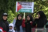 Sejumlah warga membawa bendera Palestina dan poster  long march ke liling kota saat aksi bela Palestina di Banda Aceh, Aceh, Minggu (1/12/2024). Aksi damai yang melibatkan sekitar 2.000 warga kota dan dilanjutkan penggalangan dana itu sebagai bentuk dukungan di Hari Solidaritas Internasional untuk rakyat Palestina. ANTARA FOTO/Ampelsa.