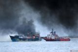 Kapal Tugboat melakukan upaya pemadaman Kapal Motor Nelayan (KMN) Bahtera yang terbakar di Selat Bali terlihat dari Pelabuhan Masami, Kalipuro, Banyuwangi, Jawa Timur, Senin (2/12/2024). Hingga saat ini petugas pemadam masih berupaya memadamkan api yang membakar dua kapal nelayan tersebut yakni KM Dinda Jaya dilakukan upaya pemadaman dari darat sedangkan KM Bahtera yang terseret arus dilakukan upaya pemadaman melalui laut menggunakan kapal tugboat dan akan di tarik ke pingir untuk mengantisipasi potensi terganggunya penyeberangan Pelabuhan ketapang-Gilimanuk. Antara Jatim/Budi Candra Setya/um