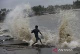 Seorang anak bermain di bibir pantai saat ombak dan angin kencang menerjang di Desa Teluk, Labuan, Kabupaten Pandeglang, Banten, Senin (2/12/2024). Badan Meteorologi, Klimatologi dan Geofisika (BMKG) mengeluarkan peringatan dini gelombang tinggi dengan kisaran 1,25 meter hingga 2,5 meter yang berpotensi terjadi di beberapa wilayah perairan Indonesia pada 2 hingga 4 Desember 2024 serta mengimbau kepada masyarakat yang tinggal dan beraktivitas di sekitar pesisir agar selalu waspada. ANTARA FOTO/Angga Budhiyanto/gp