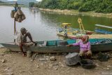 Sejumlah warga bersantai dengan latar belakang alat berat penyedot sedimen (dredger) di Bendungan Waduk Pacal, Bojonegoro, Jawa Timur, Senin (2/12/2024). Upaya tersebut dilakukan pemerintah setempat guna mengatasi pendangkalan dan penyumbatan di pintu air bendungan berkapasitas 44 juta meter kubik yang dimanfaatkan warga setempat untuk irigasi pertanian, pariwisata, dan perikanan. Antara Jatim/Muhammad Mada/um