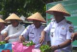 Penjabat (Pj) Wali Kota Pontianak Edi Suryanto (kiri) memberikan hasil panen sayuran kepada warga pada kegiatan Launching Gerakan Menanam Pekarangan Bergizi Cepat Panen di Jalan Petani Gg. Harapan 1 di Pontianak, Kalimantan Barat, Rabu (4/12/2024). Gerakan Menanam Perkarangan Bergizi Cepat Panen tersebut menjadi sarana pengembangan perkarangan sekitar secara optimal yang bertujuan untuk meningkatkan ketahanan pangan dan memaksimalkan pemanfaatan pekarangan. ANTARA/Kristian Jonathan