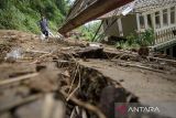 Warga melintasi jalan dan rumah yang rusak terdampak  bencana pergerakan tanah di Kadupandak, Kabupaten Cianjur, Jawa Barat, Jumat (6/12/2024). Badan Nasional Penanggulangan Bencana (BNPB) menyatakan dampak bencana geologi pergerakan tanah dari dua kecamatan di Kabupaten Cianjur tersebut mengakibatkan sebanyak 85 rumah rusak berat serta 105 unit rumah berpotensi terancam sejak peristiwa yang terjadi pada Jumat (22/11) lalu. ANTARA FOTO/Novrian Arbi/agr