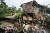 Jurnalis melihat rumah yang rusak terdampak bencana pergerakan tanah di Kadupandak, Kabupaten Cianjur, Jawa Barat, Jumat (6/12/2024). Badan Nasional Penanggulangan Bencana (BNPB) menyatakan dampak bencana geologi pergerakan tanah dari dua kecamatan di Kabupaten Cianjur tersebut mengakibatkan sebanyak 85 rumah rusak berat serta 105 unit rumah berpotensi terancam sejak peristiwa yang terjadi pada Jumat (22/11) lalu. ANTARA FOTO/Novrian Arbi/agr