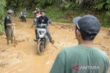 Pengendara sepeda motor melintasi jalan utama yang dipenuhi lumpur terdampak longsor di Sukanagara, Kabupaten Cianjur, Jawa Barat, Jumat (6/12/2024). Akses jalan utama penghubung Kecamatan Sukanagara dengan Kecamatan Kadupandak, Kabupaten Cianjur tersebut mulai bisa dilewati kendaraan yang sebelumnya sempat terputus selama tiga hari akibat tertimbun longsor. ANTARA FOTO/Novrian Arbi/agr