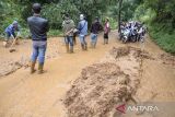 Pengendara sepeda motor menunggu petugas membersihkan jalan utama yang dipenuhi lumpur terdampak longsor di Sukanagara, Kabupaten Cianjur, Jawa Barat, Jumat (6/12/2024). Akses jalan utama penghubung Kecamatan Sukanagara dengan Kecamatan Kadupandak, Kabupaten Cianjur tersebut mulai bisa dilewati kendaraan yang sebelumnya sempat terputus selama tiga hari akibat tertimbun longsor. ANTARA FOTO/Novrian Arbi/agr