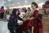 Penata rias merapikan busana yang dikenakan oleh model saat peragaan busana pengantin bertajuk Manten Expo di Kota Kediri, Jawa Timur, Minggu (8/12/2024). Peragan busana oleh sejumlah vendor jasa pernikahan se-Eks Karesidenan Kediri tersebut sebagai upaya menawarkan kebutuhan busana dan rias pengantin kepada masyarakat yang akan melangsungkan acara pernikahan. Antara Jatim/Prasetia Fauzani/um