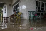 Seorang warga duduk di teras rumahnya yang terendam banjir di Desa Baros, Kecamatan Baros, Kabupaten Serang, Banten, Senin (9/12/2024). Tingginya curah hujan yang mengguyur kawasan tersebut sejak Senin (9/12) pagi disertai saluran drainase yang buruk mengakibatkan banjir di sejumlah titik dengan ketinggian mencapai sekitar 45 sentimeter. ANTARA FOTO/Angga Budhiyanto/gp