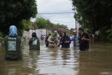 Warga melintasi jalan yang terendam banjir di Dusun Beluk, Desa Jombok, Kecamatan Kesamben, Kabupaten Jombang, Jawa Timur, Senin (9/12/2024). Dari data BPBD Kabupaten Jombang, banjir akibat luapan avour Watudakon ratusan rumah tergenang banjir dengan ketinggian bervariasi mulai 30 sentimeter hingga 60 sentimeter, selain itu sebanyak 600 jiwa terdampak serta 55 orang mengungsi ketempat aman. ANTARA Jatim/Syaiful Arif/mas.