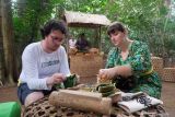 Dua wisatawan mancanegara menikmati makanan tradisional khas Bali di area hutan Samsara Living Museum, Desa Jungutan, Karangasem, Bali, Jumat (6/12/2024). Objek wisata edukasi dengan mengangkat nilai-nilai budaya tersebut menampilkan beragam sarana upacara dalam siklus hidup orang Bali yakni dari dalam kandungan hingga meninggal dunia dan menyajikan kuliner tradisional di area hutan dan dapur kuno khas Bali sebagai daya tarik pariwisata. ANTARA FOTO/Nyoman Hendra Wibowo/wsj.