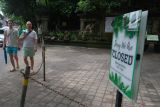 Wisatawan mancanegara melintas di depan pintu masuk objek wisata Monkey Forest di Ubud, Gianyar, Bali, Rabu (11/12/2024). Objek wisata tersebut ditutup sementara imbas dua wisatawan mancanegara meninggal dunia akibat tertimpa pohon tumbang pada Selasa (10/12/2024). ANTARA FOTO/Nyoman Hendra Wibowo/wsj.