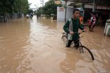 Remaja berusaha mengayuh sepedanya melintasi jalan yang terendam banjir di Kelurahan Kelutan, Trenggalek, Jawa Timur, Senin (16/12/2024). Banjir bandang itu menyebabkan jalur utama Trenggalek-Tulungagung putus total dan ribuan rumah di dua kelurahan pusat Kota Trenggalek (Kelurahan Kelutan dan Tamanan) terendam hingga ketinggian air 1,5 meter imbas jebolnya tanggul Sungai Ngasinan pasca turun hujan deras selama beberapa jam sejak Minggu (15/12/2024) malam. Antara Jatim/Destyan Sujarwoko/um