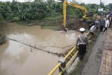 Pekerja mengoperasikan alat berat untuk membersihkan aneka sampah kayu dan akar rumpun (barongan) bambu yang tersangkut di tiang jembatan Punjung, Trenggalek, Jawa Timur, Senin (16/12/2024). Normalisasi dilakukan untuk mencegah risiko kerusakan pada badan jembatan sekaligus melancarkan aliran air sungai agar banjir tidak meluap ke pemukiman. Antara Jatim/Destyan Sujarwoko/um