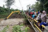 Pekerja mengoperasikan alat berat untuk membersihkan aneka sampah kayu dan akar rumpun (barongan) bambu yang tersangkut di tiang jembatan Punjung, Trenggalek, Jawa Timur, Senin (16/12/2024). Normalisasi dilakukan untuk mencegah risiko kerusakan pada badan jembatan sekaligus melancarkan aliran air sungai agar banjir tidak meluap ke pemukiman. Antara Jatim/Destyan Sujarwoko/um