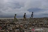 Tiga orang anak berjalan di atas tumpukan sampah yang terbawa gelombang tinggi di Desa Teluk, Labuan, Kabupaten Pandeglang, Banten, Senin (16/12/2024). Gelombang tinggi yang terjadi di perairan Banten sejak beberapa hari terakhir mengakibatkan sejumlah warung di kawasan pesisir rusak, menumpuknya sampah akibat terbawa gelombang, serta membuat nelayan setempat tidak dapat melaut untuk sementara waktu. ANTARA FOTO/Angga Budhiyanto/gp