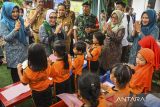 Menteri Pemberdayaan Perempuan dan Perlindungan Anak (PPPA) Arifah Fauzi (kedua kiri) menyapa sejumlah siswa saat mengunjungi Kampung Jimpitan, Kota Tangerang, Banten, Senin (16/12/2024). Dalam kunjungannya, MenPPPA Arifah Fauzi menyosialisasikan program prioritasnya yakni Ruang Bersama Indonesia, perluasan fungsi layanan pengaduan, serta satu data tentang perempuan dan anak berbasis desa. ANTARA FOTO/Sulthony Hasanuddin/gp