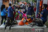 Petugas pemadam kebakaran memperkenalkan alat pelindung diri kepada siswa Taman Kanak-kanak (TK) dan pendidikan anak usia dini (PAUD) saat edukasi kinerja profesi pemadam kebakaran di halaman kantor BPBD Kabupaten Serang, Kota Serang, Banten, Rabu (18/12/2024). Sebanyak 20 siswa TK dan sembilan siswa PAUD mengikuti kegiatan tesebut yang bertujuan untuk memperkenalkan profesi dan tugas petugas pemadam kebakaran, sosialisasi mencegah kebakaran, penyelamatan hewan, serta memberikan pengetahuan tentang evakuasi atau penyelamatan diri saat terjadi bencana alam kepada anak usia dini. ANTARA FOTO/Angga Budhiyanto/gp