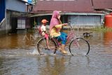 Pengendara sepeda melintasi jalan yang tergenang banjir rob di Sungai Kakap, Kabupaten Kubu Raya, Kalimantan Barat, Selasa (17/12/2024). BMKG Kalbar memprakirakan puncak air pasang di Kota Pontianak dan sekitarnya terjadi pada 18-20 Desember 2024. ANTARA FOTO/Jessica Wuysang/tom.