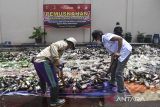 Petugas melemparkan botol minuman keras saat pemusnahan barang bukti minuman keras di Mako Polres Tasikmalaya, Singaparna, Kabupaten Tasikmalaya, Jawa Barat, Kamis (19/12/2024). Polres Tasikmalaya memusnahkan sebanyak 10 ribu botol miras dan 200 knalpot bising hasil sitaan operasi pekat 2024 untuk mencegah penyakit masyarakat jelang perayaan malam Tahun Baru 2025. ANTARA FOTO/Adeng Bustomi/agr