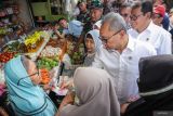 Menko Bidang Pangan Zulkifli Hasan (kedua kanan) didampingi Menteri Perdagangan Budi Santoso (kanan) membagikan bantuan uang tunai kepada warga saat kunjungan kerja di Pasar Dukuh Kupang, Surabaya, Jawa Timur, Jumat (20/12/2024). Dalam kunjungan kerjanya, Menko Bidang Pangan dan Mendag meninjau ketersediaan pasokan dan harga bahan pokok di pasar tradisional jelang Natal dan Tahun Baru 2025. ANTARA FOTO/Rizal HanafiANTARA FOTO/Rizal Hanafi (ANTARA FOTO/Rizal Hanafi)