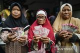 Warga memperlihatkan uang tunai bantuan sosial program keluarga harapan di Kantor Kecamatan Cikande, Kabupaten Serang, Banten, Sabtu (21/12/2024). Kementerian Sosial telah menyalurkan 97 persen program bantuan sosial dan ditargetkan penyaluran selesai 100 persen dalam sembilan hari ke depan. ANTARA FOTO/Putra M. Akbar/gp