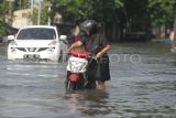 Warga mendorong motor saat menerobos banjir di Jalan Raya Pepelegi, Waru, Sidoarjo, Jawa Timur, Rabu (25/12/2024). Intensitas curah hujan tinggi di kawasan Waru serta sungai yang tidak dapat menampung debit air menyebabkan banjir di belasan desa dengan ketinggian air sekitar 30-60 cm. ANTARA FOTO/Umarul Faruq/wpa. 