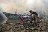 Petugas terperosok saat berusaha memadamkan kapal nelayan yang terbakar di Pelabuhan Tegal, Jawa Tengah, Jumat (27/12/2024). Pemadam kebakaran dan warga kesulitan memadamkan api yang membakar 13 kapal nelayan akibat akses jalan sulit, angin besar dan banyak oli di atas kapal. ANTARA FOTO/Oky Lukmansyah/nym. 