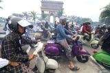 Sejumlah peserta mengendarai skuter Vespa dengan latar belakang Monumen Simpang Lima Gumul saat kegiatan bertajuk Scooter Sarungan di Kediri, Jawa Timur, Minggu (29/12/2024). Touring skuter Vespa menempuh jarak 22 kilometer yang diikuti oleh sedikitnya tiga ribu peserta bersarung tersebut guna memperingati 100 tahun berdirinya pondok pesantren Al-Falah Ploso Kediri. Antara Jatim/Prasetia Fauzani/um