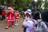 Petugas menggunakan pakaian santa melambaikan tangan saat menghibur pengunjung di Kebun Binatang Bandung, Jawa Barat, Rabu (25/12/2024). Kebun Binatang Bandung menargetkan sebanyak 1.500 pengunjung per hari selama libur Natal dan Tahun Baru 2025 dari periode 21 Desember 2024 hingga 5 Januari 2025. ANTARA FOTO/Raisan Al Farisi/agr
