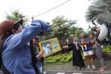Pemotret komersial memotret kliennya di depan Kebun Binatang Surabaya, Jawa Timur, Rabu (1/1/2025). Jasa foto itu mematok harga Rp10 ribu sampai Rp20 ribu per lembar. Antara Jatim/Didik Suhartono/um