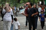 Pemotret komersial menawarkan jasa foto kepada pengunjung di depan Kebun Binatang Surabaya, Jawa Timur, Rabu (1/1/2025). Jasa foto itu mematok harga Rp10 ribu sampai Rp20 ribu per lembar. Antara Jatim/Didik Suhartono/um