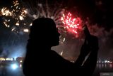 Warga menyaksikan kembang api saat malam pergantian tahun di Pantai Mertasari Sanur, Denpasar, Bali, Rabu (1/1/2025). Pemerintah Kota Denpasar memusatkan pesta kembang api perayaan Tahun Baru 2025 di objek wisata tersebut untuk keamanan dan kenyamanan masyarakat. ANTARA FOTO/Nyoman Hendra Wibowo/wsj.