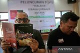 Seorang jurnalis membaca buku berjudul 