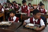 Siswa membuka kotak berisi makanan dalam pelaksanaan Program Makan Bergizi Gratis (MBG) di SDN 1 Tamanharjo, Singosari, Malang, Jawa Timur, Senin (6/1/2025). Pelaksanaan perdana Program  Makan Bergizi Gratis (MBG) perdana tersebut dilaksanakan pihak TNI AU dengan menyasar 27 sekolah di sekitar kawasan Lanud Abdul Rahman Saleh dengan jumlah 4.005 porsi per hari. Antara Jatim/Ari Bowo Sucipto/um