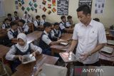 Wakil Menteri Pemuda dan Olahraga (Wamenpora) Taufik Hidayat (kanan) membagikan paket makan bergizi gratis (MBG) di SMPN 12 Cimahi, Kota Cimahi, Jawa Barat, Senin (6/1/2025). Dalam kunjungan kerja tersebut Menpora Dito Ariotedjo dan Wamenpora Taufik Hidayat berkesempatan untuk meninjau proses pengemasan menu makan bergizi gratis (MBG) di Satuan Pelayanan Pemenuhan Gizi serta pelaksanaan program makan bergizi gratis di sekolah. ANTARA FOTO/Abdan Syakura/agr