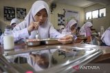 Siswa menyantap makanan bergizi gratis di SMPN 12 Cimahi, Kota Cimahi, Jawa Barat, Senin (6/1/2025). Pelaksanaan perdana program Makan Bergizi Gratis (MBG) dilakukan secara bertahap di sejumlah sekolah di Kota Cimahi, mencakup jenjang TK/PAUD, SD, SMP, dan SMA/SMK sederajat hingga Pos Pelayanan Terpadu (Posyandu) dengan total 3.500 porsi paket makanan disediakan setiap hari. ANTARA FOTO/Abdan Syakura/agr
