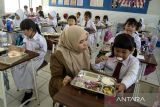 Guru memantau siswi menyantap makanan bergizi gratis di SD Angkasa 1, Bandung, Jawa Barat, Senin (6/1/2025). Pemerintah Kota Bandung akan mengevaluasi kualitas pemenuhan asupan gizi dari paket makanan yang diterima oleh sedikitnya 6500 pelajar se-Kota Bandung pada saat tiga bulan program makanan bergizi gratis nasional telah dilaksanakan. ANTARA FOTO/Novrian Arbi/agr
