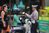 Personel Satlantas Polres Badung menindak pengemudi ojek daring yang melanggar aturan lalu lintas karena mengangkut wisatawan tanpa menggunakan helm di kawasan Kerobokan, Badung, Bali, Senin (6/1/2025). Penindakan berupa tilang tersebut terus dilakukan karena masih tingginya pengguna jalan khususnya warga negara asing (WNA) yang melanggar aturan berlalu lintas di berbagai titik kawasan wisata di Bali. ANTARA FOTO/Fikri Yusuf/wsj.