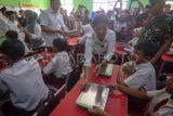 Menteri Komunikasi dan Digital Meutya Hafid (tengah) memberikan kotak makanan kepada siswa saat meninjau pelaksanaan Program Makan Bergizi Gratis di SDN Cilangkap 5, Depok, Jawa Barat, Senin (6/1/2025). Pemerintah resmi memulai Program Makan Bergizi Gratis yang dilaksanakan serentak di 26 Provinsi di Indonesia. ANTARA FOTO/Yulius Satria Wijaya/nz.