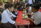 Menteri Komunikasi dan Digital Meutya Hafid (kiri) berbincang dengan seorang siswa saat meninjau pelaksanaan Program Makan Bergizi Gratis di SDN Cilangkap 5, Depok, Jawa Barat, Senin (6/1/2025). Pemerintah resmi memulai Program Makan Bergizi Gratis yang dilaksanakan serentak di 26 Provinsi di Indonesia. ANTARA FOTO/Yulius Satria Wijaya/nz.