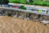 Foto udara jalan Raya Mliriprowo ambrol tergerus air sungai bendungan Rolak Songo di Desa Mliriprowo, Tarik, Sidoarjo, Jawa Timur, Selasa (7/1/2025). Intensitas hujan tinggi dalam beberapa hari terakhir membuat debit air Sungai Brantas di pintu dam Rolak Songo mengalami peningkatan mengakibatkan jalan Raya Mliriprowo ambrol tergerus air sungai. Antara Jatim/Umarul Faruq