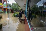 Penjaga sekolah menengok ruang kelas yang terdampak banjir di SD Negeri 1 Kedaleman, Kota Cilegon, Banten, Kamis (9/1/2025). Menurut pihak sekolah, sebanyak 600 siswa di sekolah tersebut terpaksa dipulangkan lebih awal akibat sebagian ruang kelas, halaman sekolah, serta ruang guru terendam banjir sehingga mengganggun aktivitas kegiatan belajar mengajar. ANTARA FOTO/Muhammad Bagus Khoirunas/gp