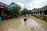 Penjaga sekolah menengok ruang kelas yang terdampak banjir di SD Negeri 1 Kedaleman, Kota Cilegon, Banten, Kamis (9/1/2025). Menurut pihak sekolah, sebanyak 600 siswa di sekolah tersebut terpaksa dipulangkan lebih awal akibat sebagian ruang kelas, halaman sekolah, serta ruang guru terendam banjir sehingga mengganggun aktivitas kegiatan belajar mengajar. ANTARA FOTO/Muhammad Bagus Khoirunas/gp